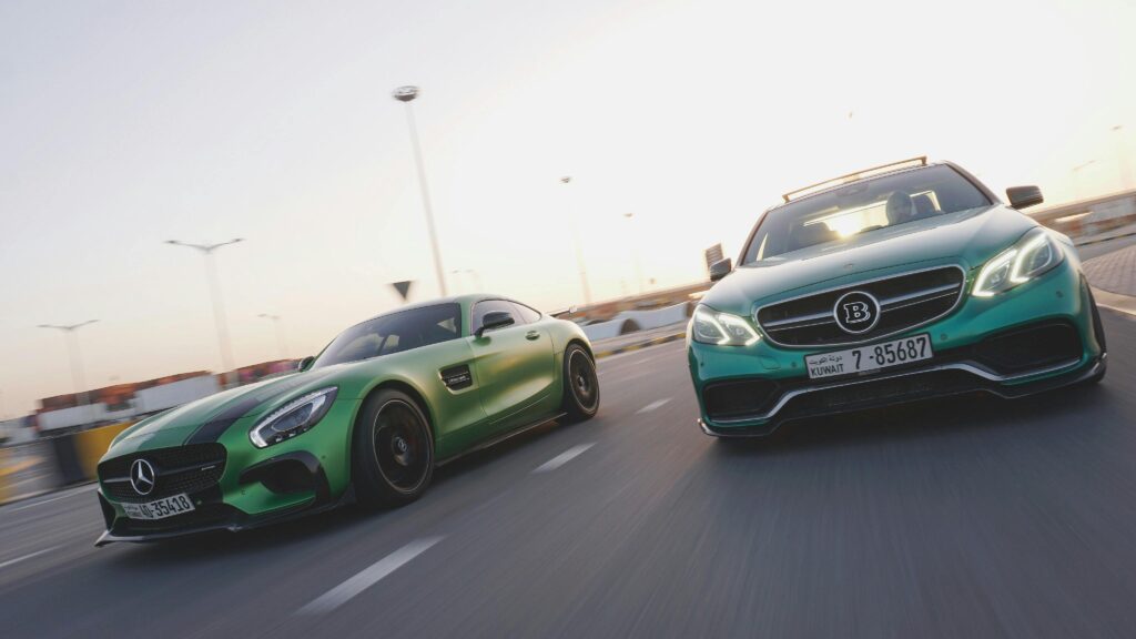 Two luxury sports cars race on a highway in Kuwait during sunset, symbolizing speed and freedom.